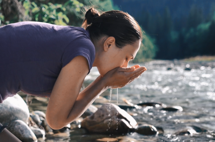 Woman drinking river water using hands