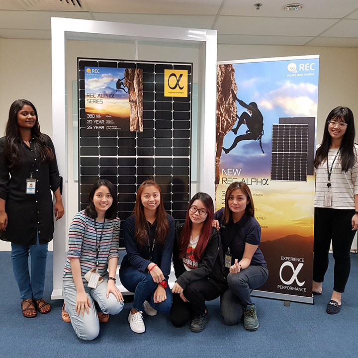 Female REC employees standing with an REC Alpha solar panel