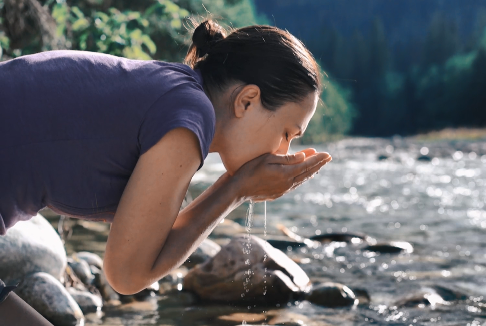 Woman drinking river water using hands